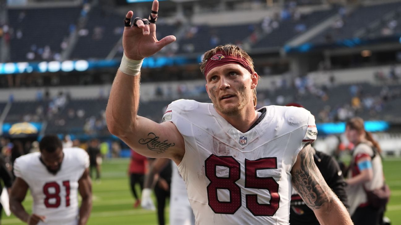 Arizona Cardinals player wearing number 85 raises a hand on the field after a game.