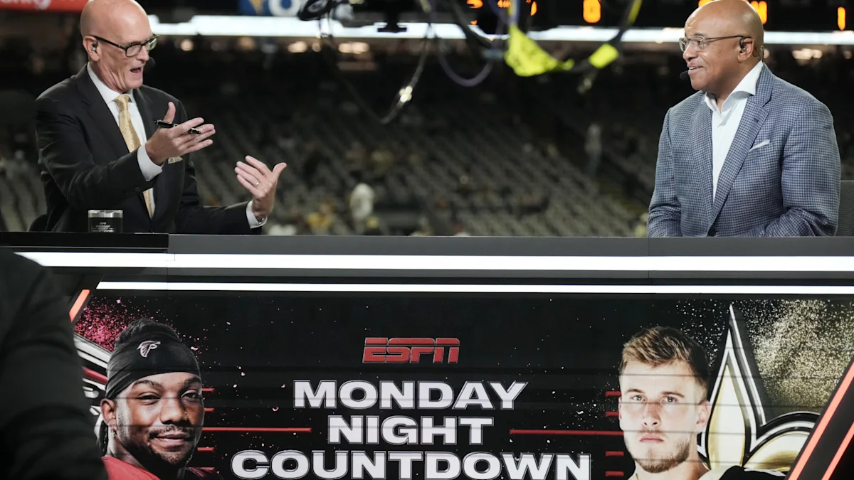 Two football commentators talk above an ESPN Monday Night Countdown graphic featuring Falcons and Saints players.