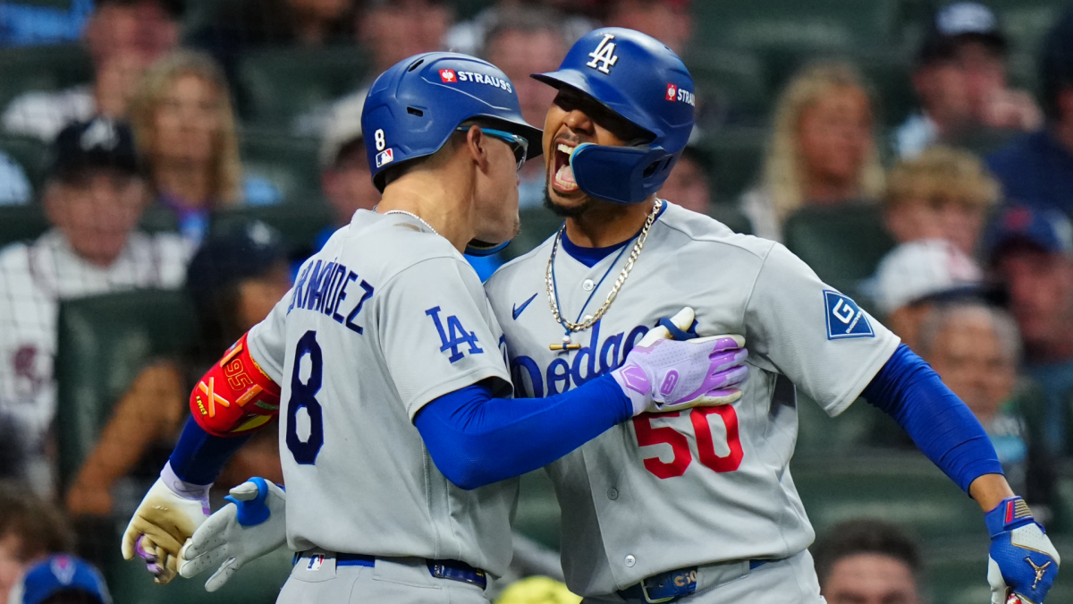 Two Dodgers players in gray uniforms celebrate face-to-face, one patting the other's chest.