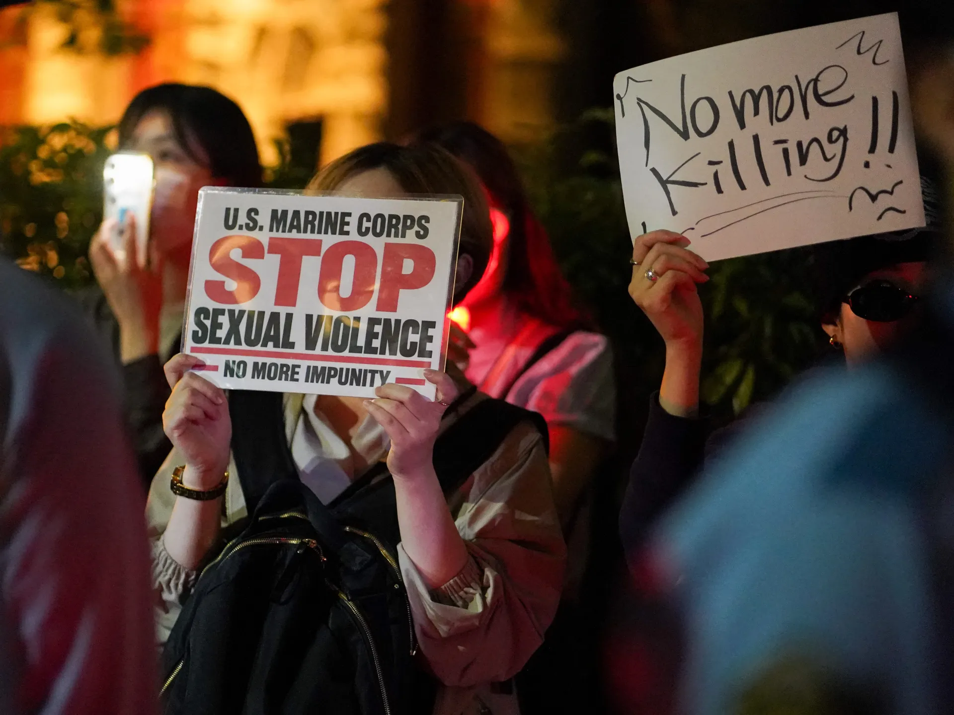 Protesters hold signs opposing sexual violence and calling for an end to killing at night.