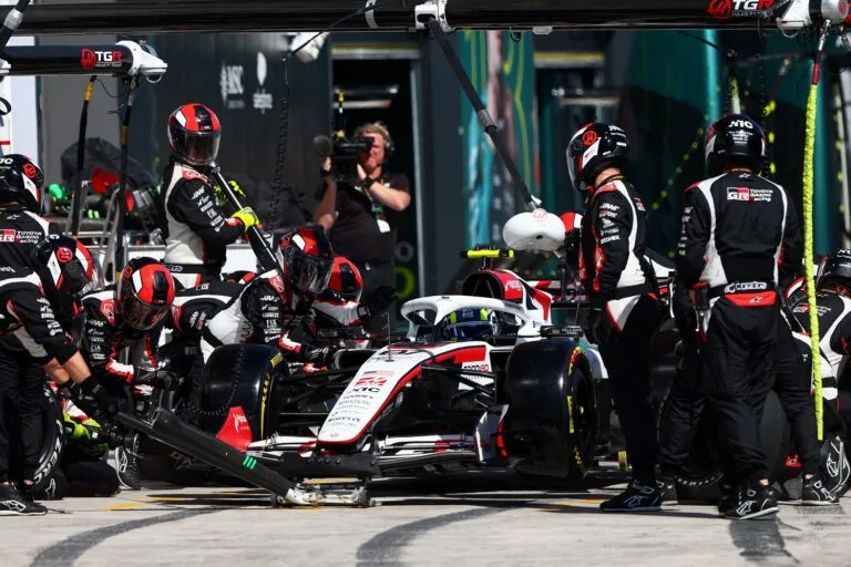 Haas crew members surround a white, red and black Formula One car in the garage.