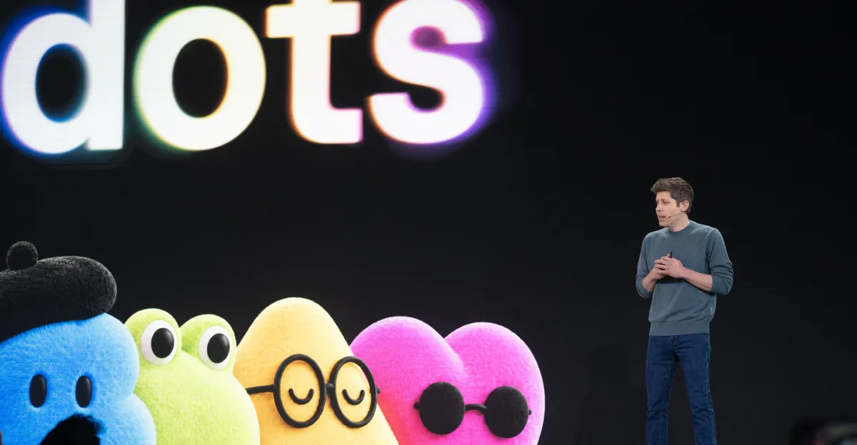 A man stands beside colorful fuzzy characters beneath large, cropped letters on a dark stage.