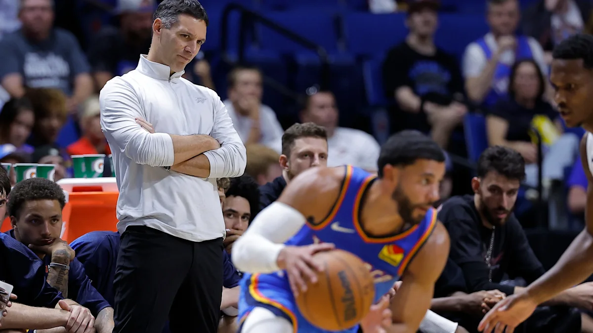 A Thunder player drives with the ball as a coach watches from the sideline during a game.