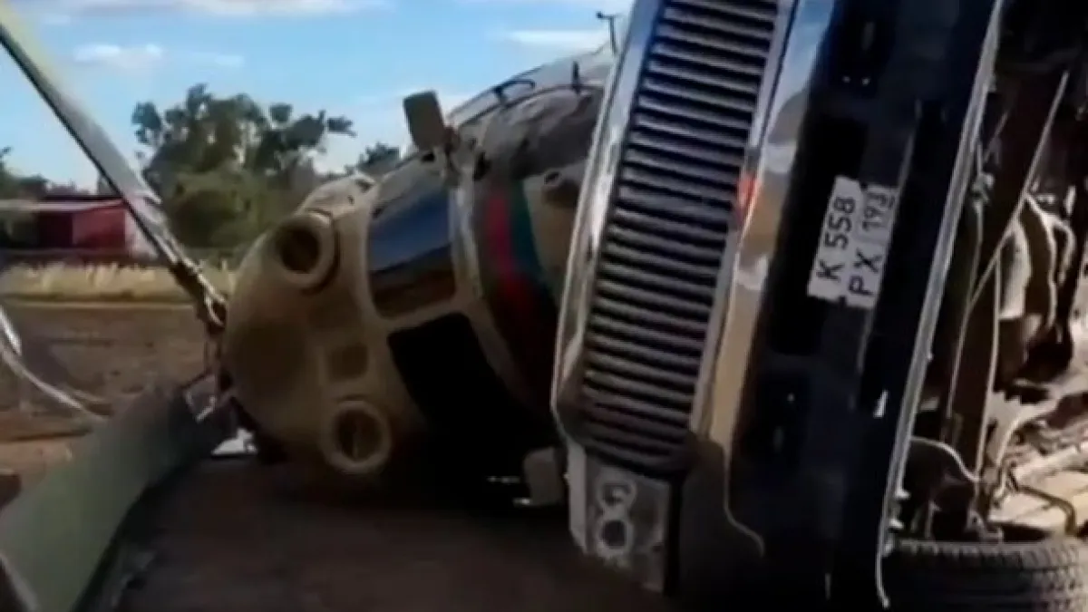 A large helicopter lies on its side beside a pickup truck on a rural road.