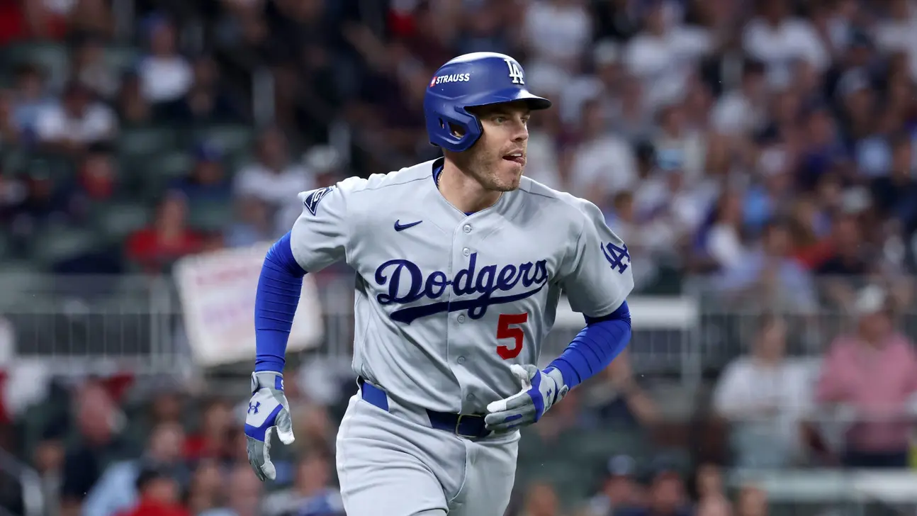 A Dodgers player wearing number five runs across the field during a baseball game.