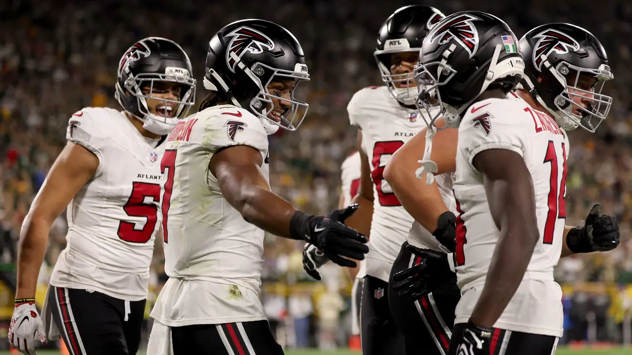 Atlanta Falcons players in white uniforms gather on the field during a game.
