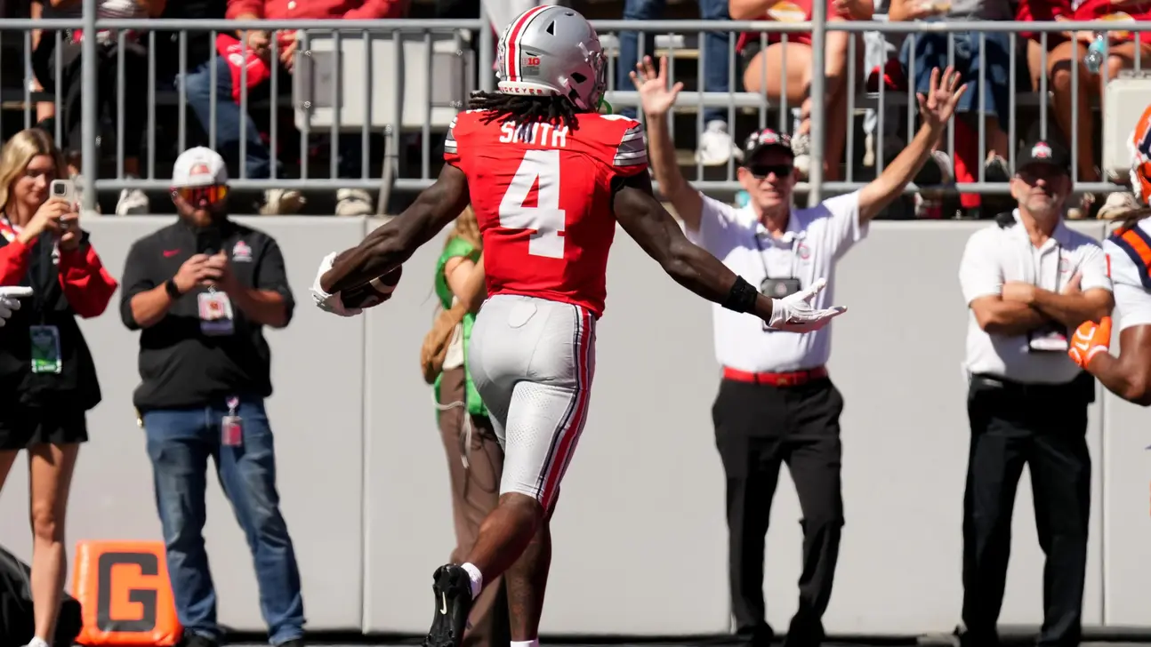 Ohio State player wearing No. 4 celebrates with arms outstretched near the sideline.
