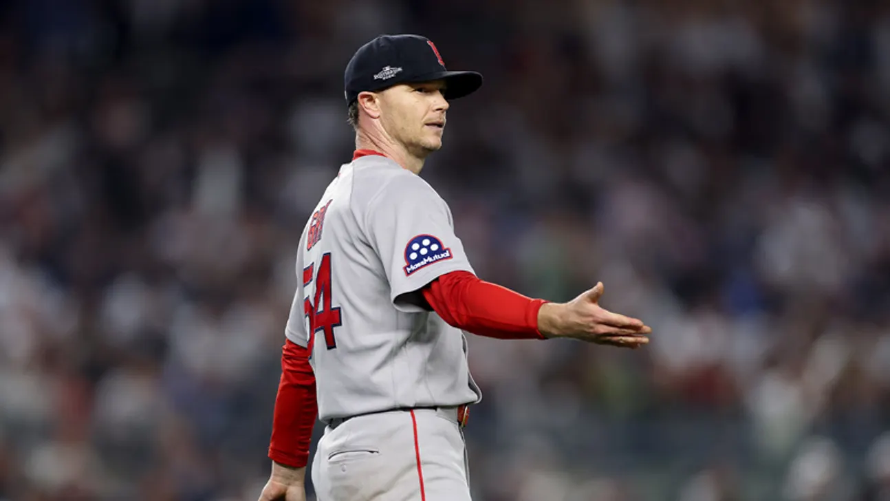 A baseball player in a gray uniform gestures with an open hand during a game.
