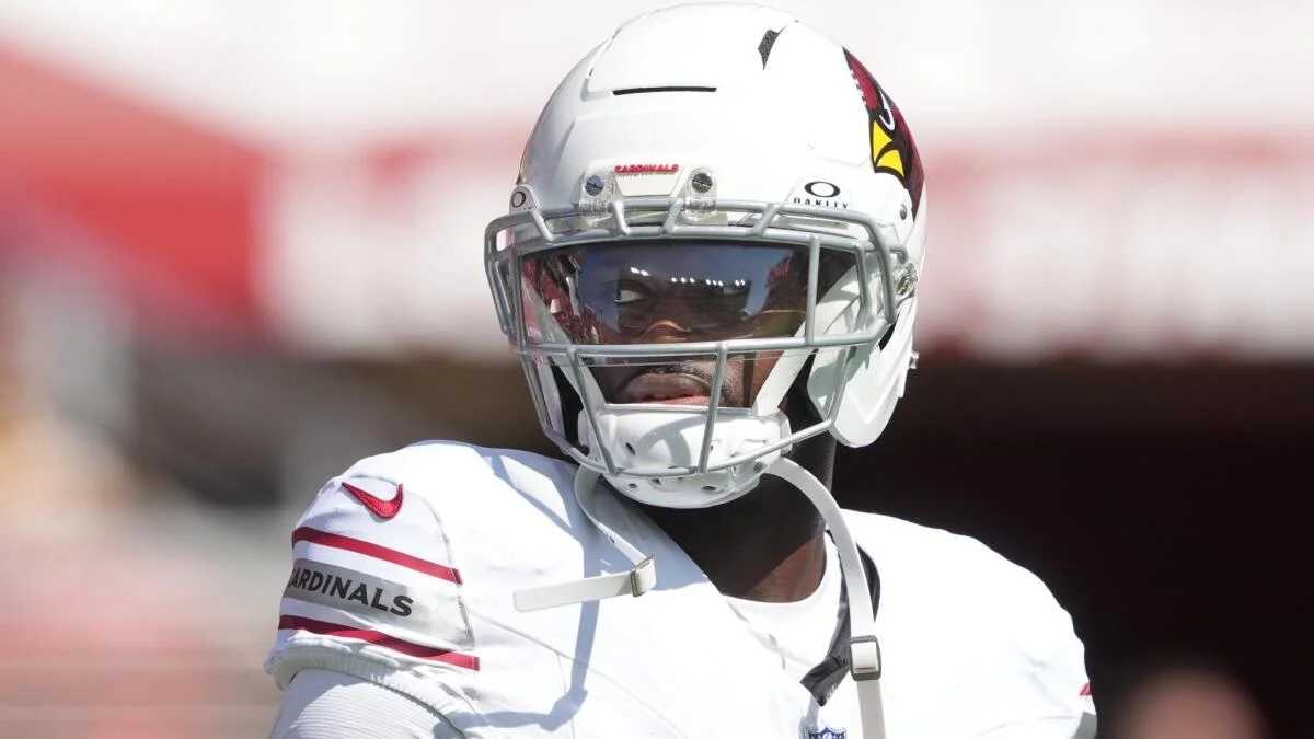 Football player wearing a white helmet and white uniform with a dark visor and face mask.