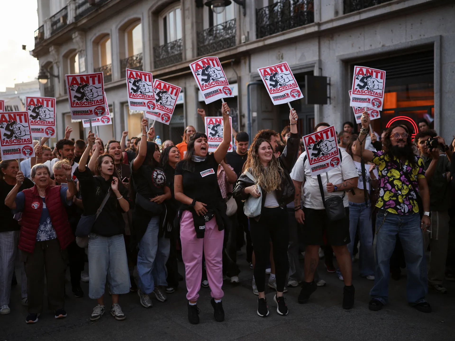 Crowd of demonstrators holding anti-fascist signs outside a city building.