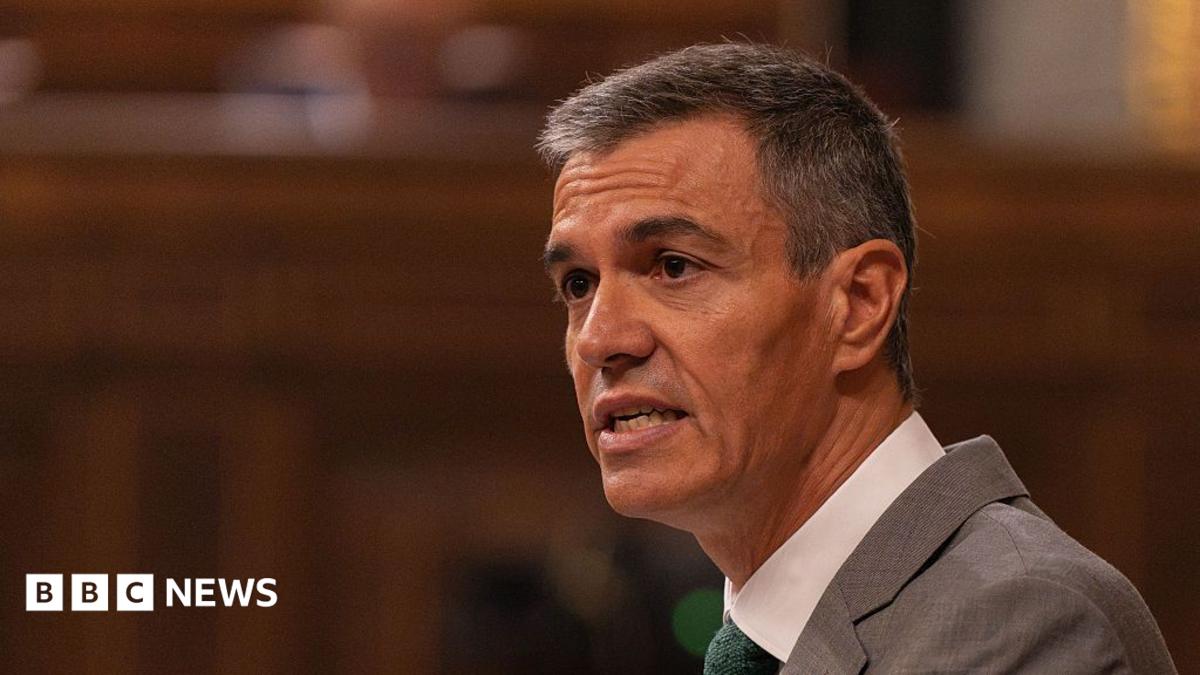 A gray-haired man in a suit speaks in a warmly lit indoor setting, with a BBC News logo.
