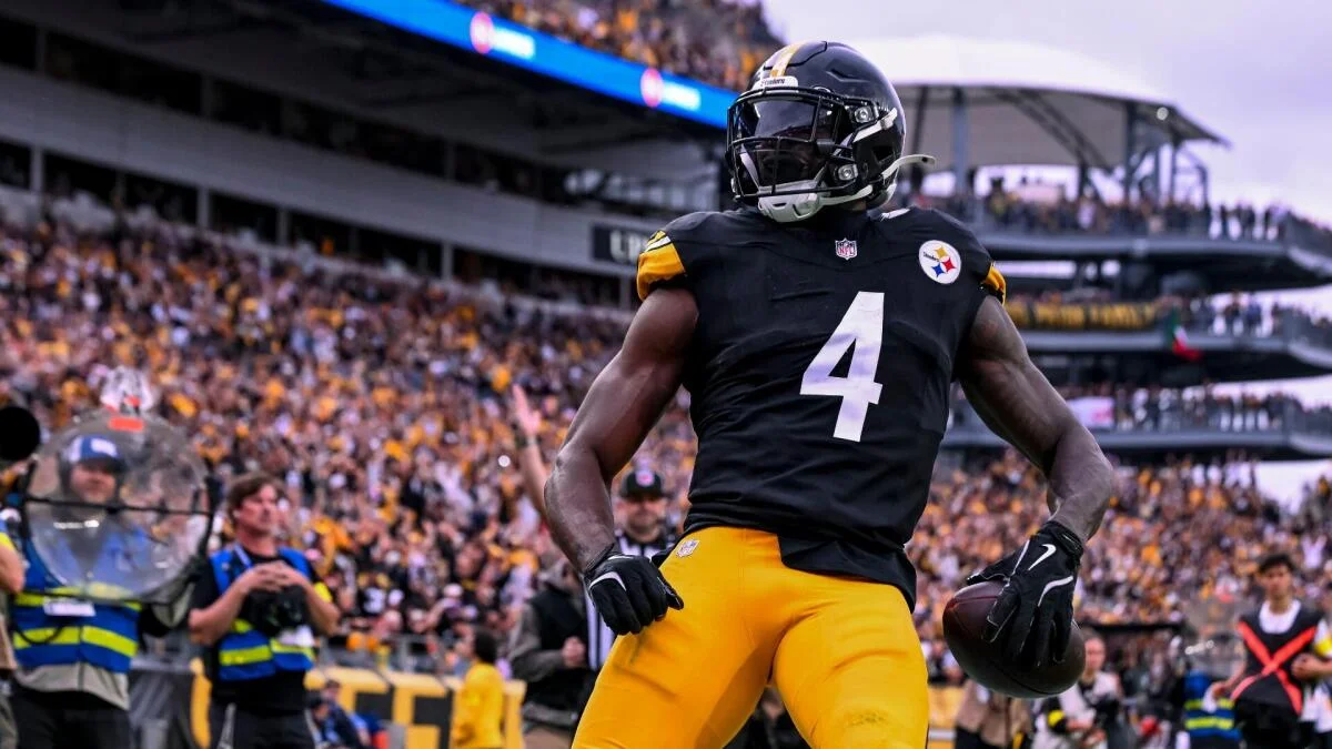 A Pittsburgh Steelers player wearing number 4 stands on the field with a football in a crowded stadium.