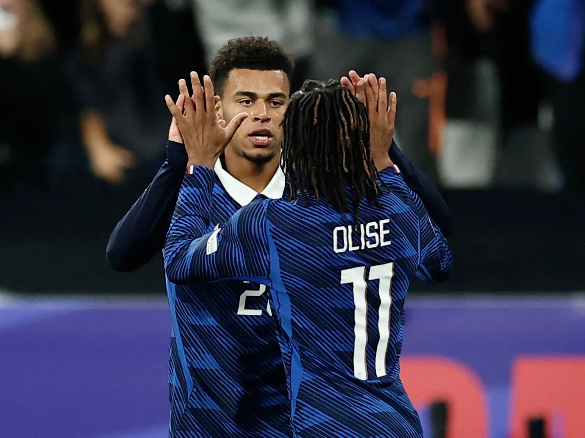 Two France players in blue jerseys celebrate with raised hands during a match.