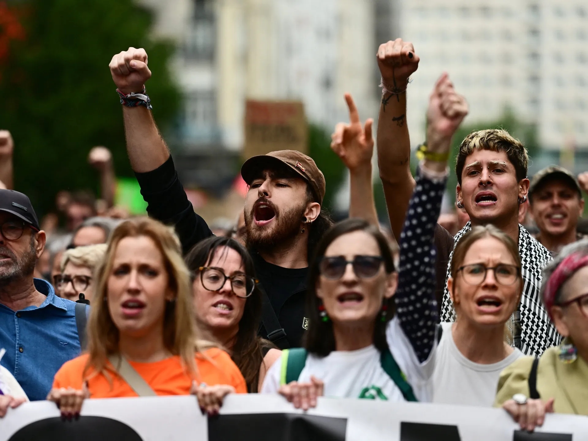 Crowd of demonstrators raise fists and hold a banner during a street protest.