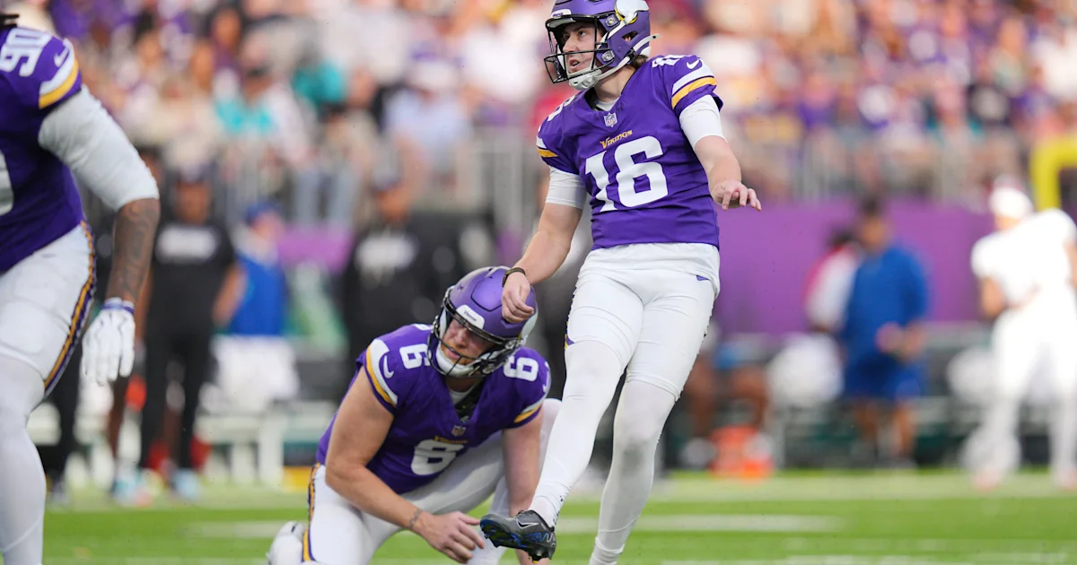 A Vikings holder kneels as kicker number 16 prepares to kick during a game.