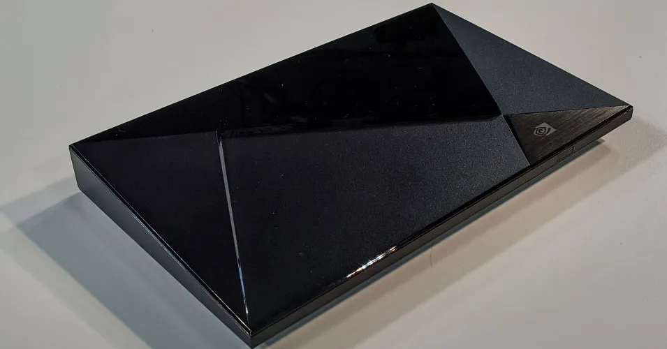 A black, angular Nvidia Shield TV device sits on a light-colored surface.