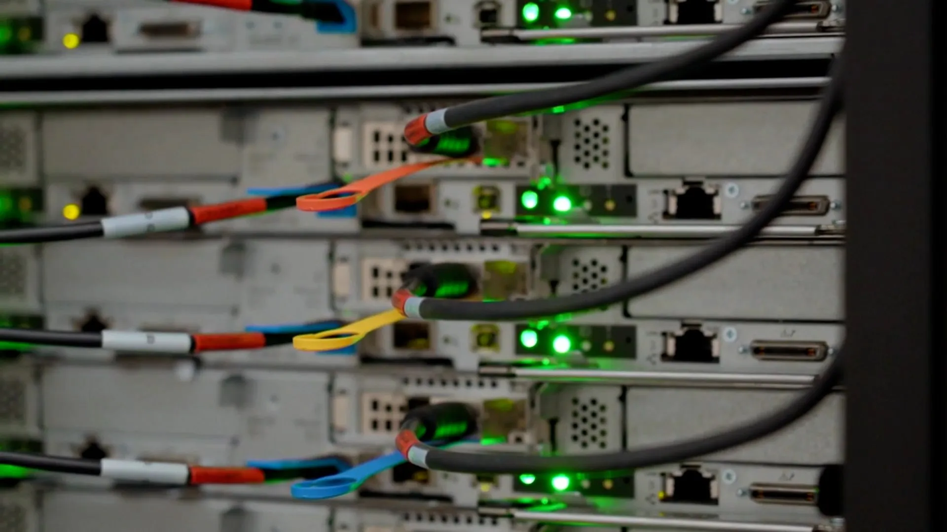 Cables connect rows of server equipment, with green indicator lights glowing across the rack.
