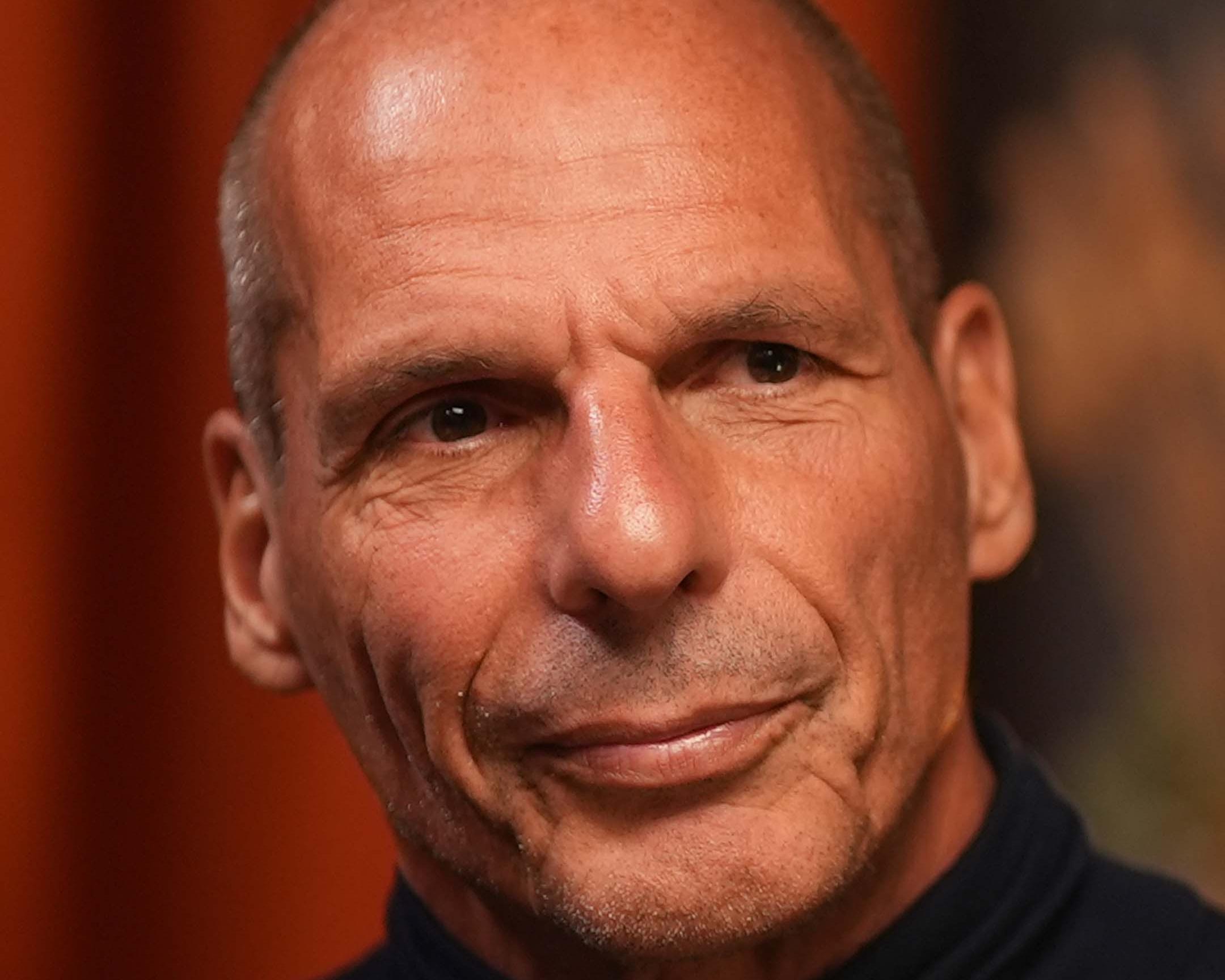 Close-up portrait of a bald man with a slight smile against a softly blurred warm-toned background.