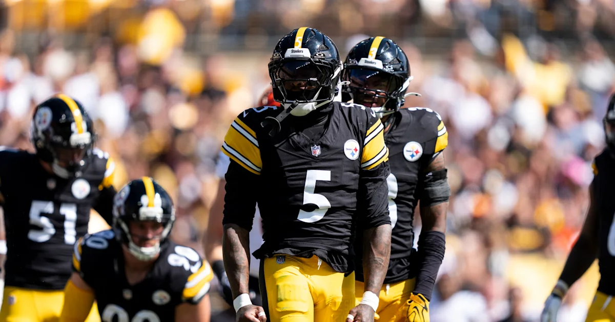 Pittsburgh players in black and gold uniforms walk across the field before a game.