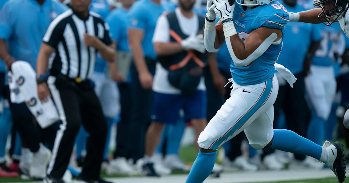 A Tennessee Titans player in a blue uniform runs with the ball during a football game.