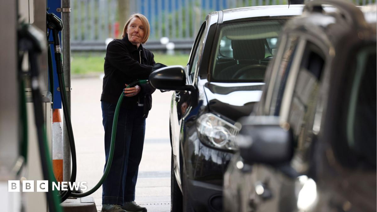 A woman refuels a black car at a fuel pump, with another vehicle in the foreground.
