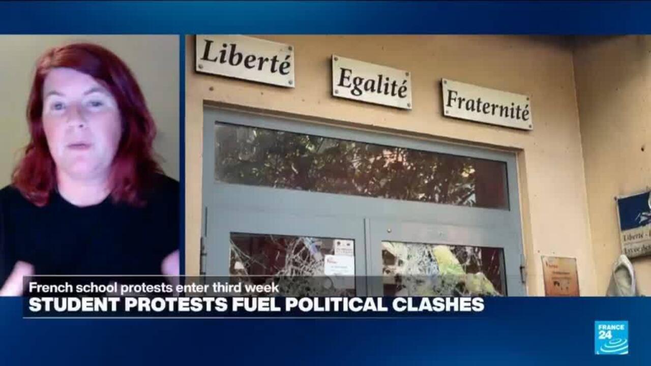 Split-screen news broadcast shows a red-haired woman speaking beside a school entrance with shattered windows.