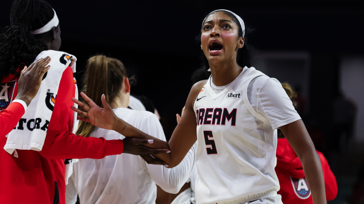 Atlanta Dream player in a white number five jersey celebrates with teammates after a game.