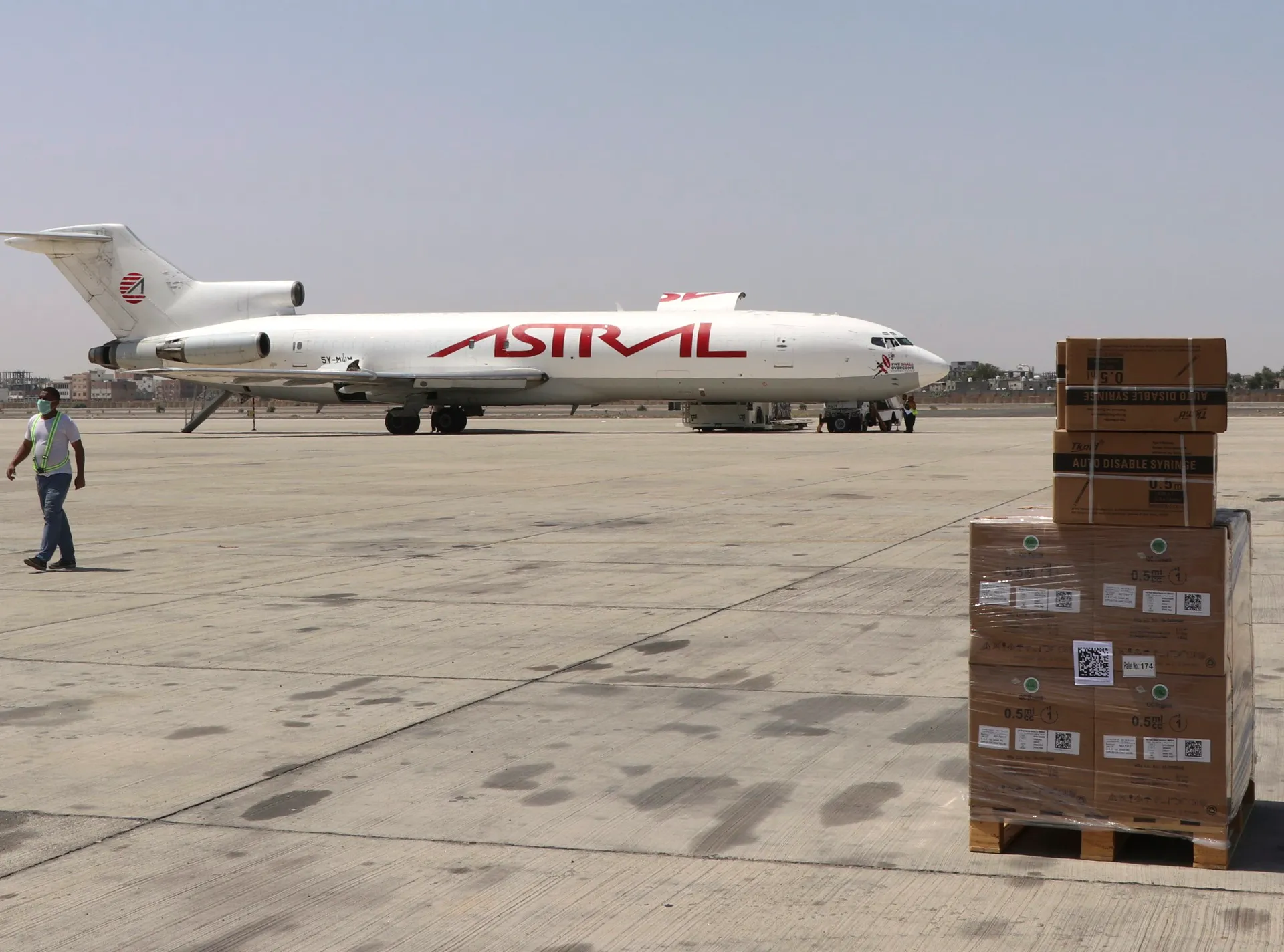 A cargo plane with STRAAL lettering sits on an airport apron beside stacked medical supply boxes.